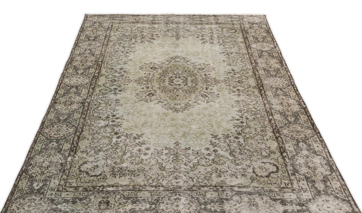 Distressed sage green and brown vintage-style rug with a central medallion and ornate floral border on a white background.