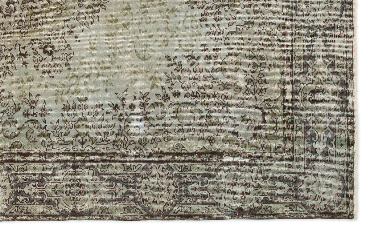 Distressed sage green and brown traditional rug with an intricate floral medallion pattern and a wide decorative border.