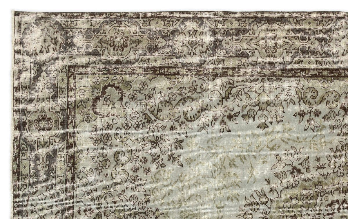 Distressed sage green and brown rug with a traditional floral medallion border and intricate vine patterns.
