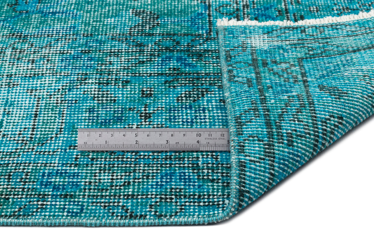 Teal and black distressed medallion rug with a white fringe, shown with a metal ruler for scale.