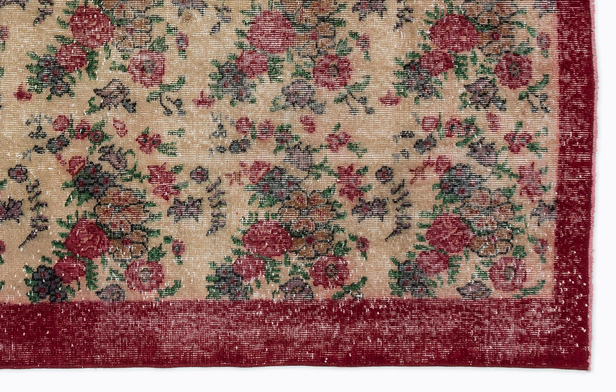 Beige rug with a distressed floral pattern in red, green, and dark grey, featuring a solid red border.