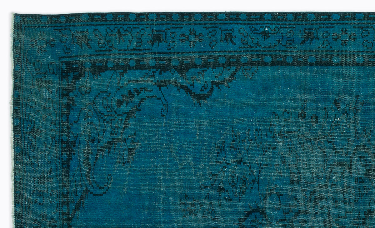 Teal and black distressed rug with a traditional ornate border and faded floral medallion pattern.