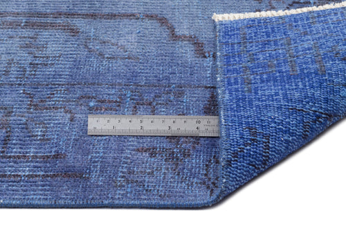 Load image 1 in gallery view. Blue rug with a dark charcoal distressed pattern, shown folded with a metal ruler for scale on a white background.