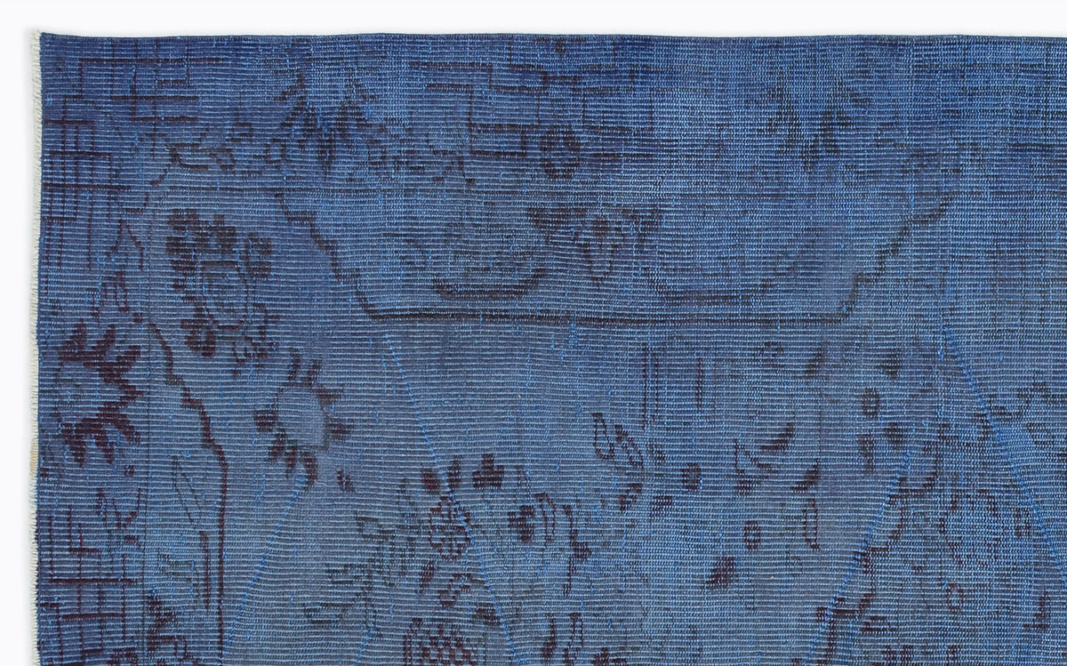 Deep blue rug with a dark, distressed floral and geometric line pattern on a white background.