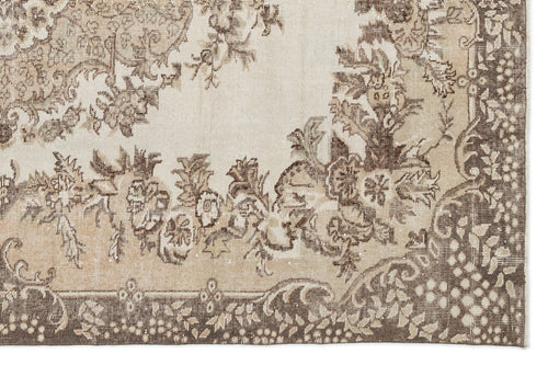 Load image 1 in gallery view. A close-up of the Hakeon - Vintage Medallion Rug (6'5" x 9'8"), inspired by Anatolian designs, features ornate beige and brown floral patterns, a faded distressed look, and decorative borders along the right and bottom edges.
