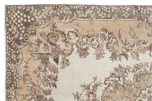 Load image 1 in gallery view. The Hakeon Vintage Medallion Rug (6'5" x 9'8") features a faded floral and ornate medallion pattern in beige, brown, and tan, with intricate borders and distressed details for an authentic antique look.