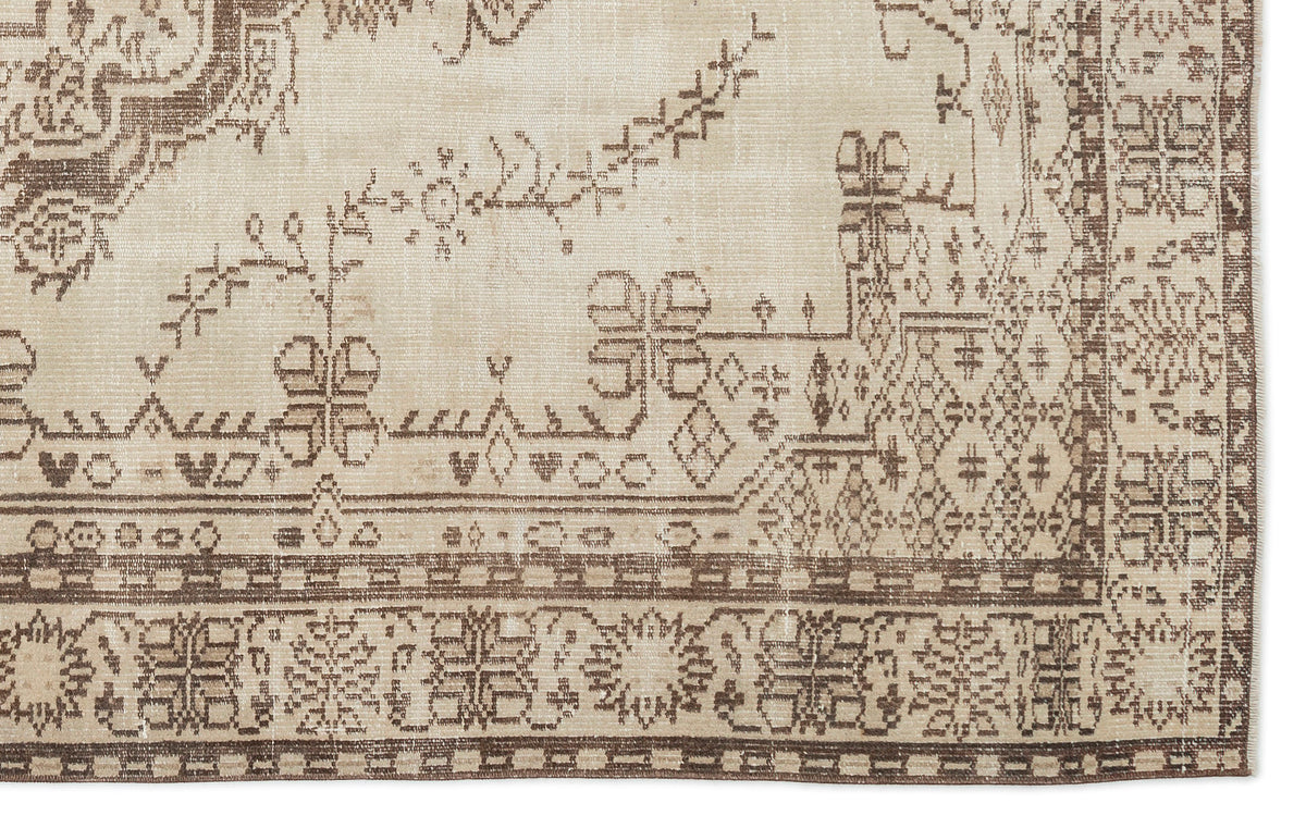 Corner of the Kidaen - Vintage Medallion Rug (6'0 X 9'6) in beige and brown, featuring intricate geometric and floral border designs with lighter, faded central motifs for a vintage look.