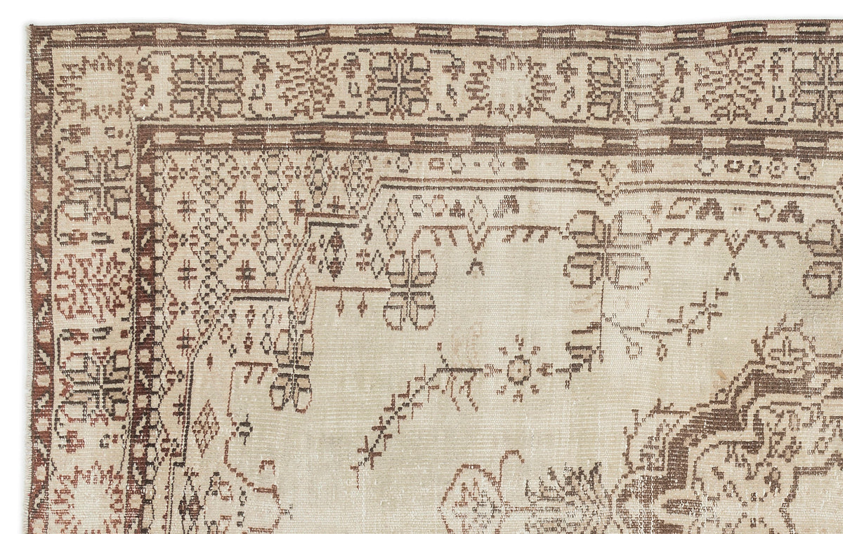 A close-up of the Kidaen - Vintage Medallion Rug (6'0 x 9'6) shows intricate geometric and floral patterns in muted beige and brown tones, with detailed borders and gently worn, faded areas.
