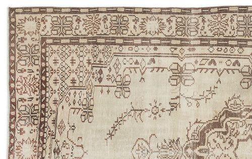 Load image 1 in gallery view. A close-up of the Kidaen - Vintage Medallion Rug (6'0 x 9'6) shows intricate geometric and floral patterns in muted beige and brown tones, with detailed borders and gently worn, faded areas.