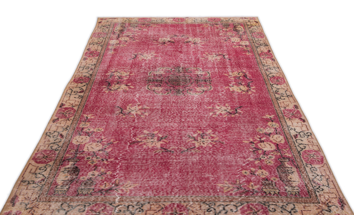Distressed magenta rug with a central medallion, floral motifs, and a beige border on a white background.