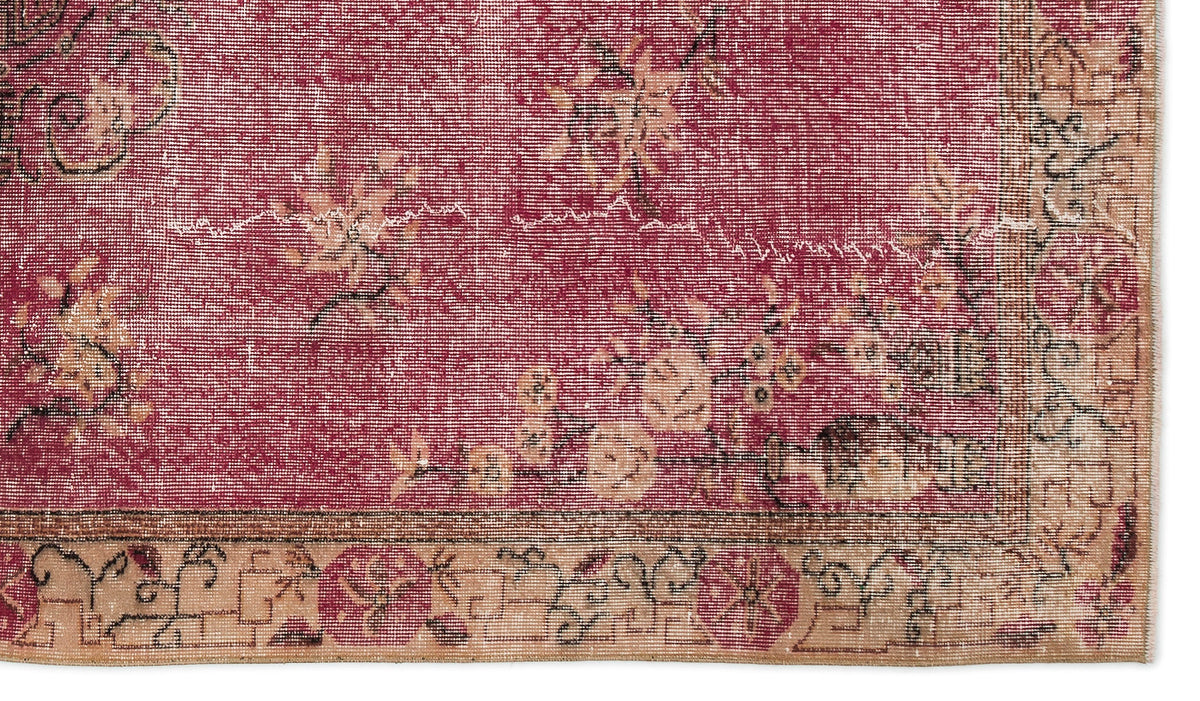 Distressed crimson rug with a faded floral pattern and a tan geometric border on a white background.