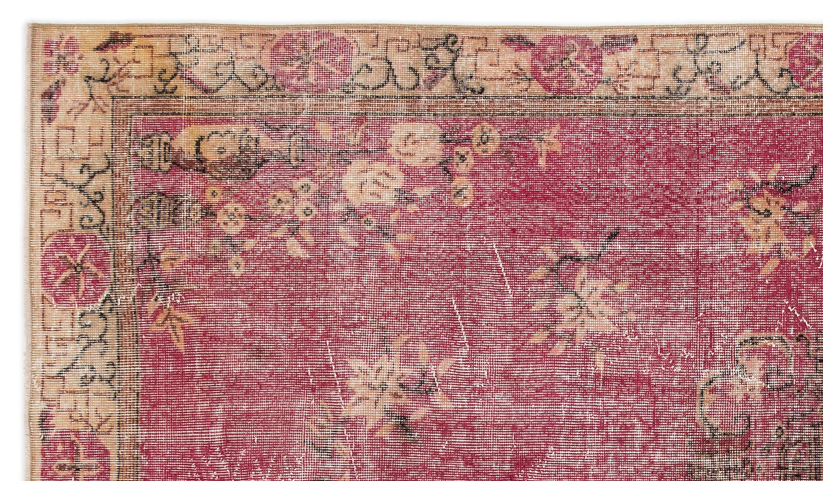 Distressed magenta rug with a beige floral border and scattered cream blossom motifs.