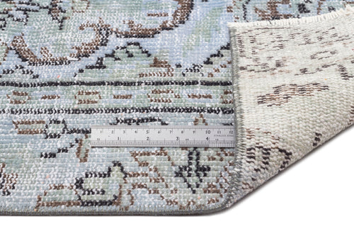 Load image 1 in gallery view. Light blue and cream distressed rug with a traditional floral pattern and a metal ruler showing pile texture.