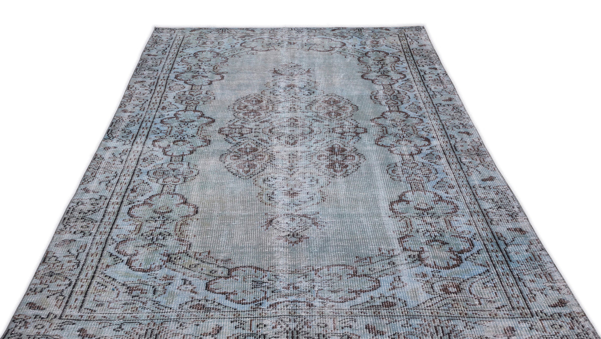 Light blue and brown distressed area rug with a traditional central medallion and ornate border pattern.