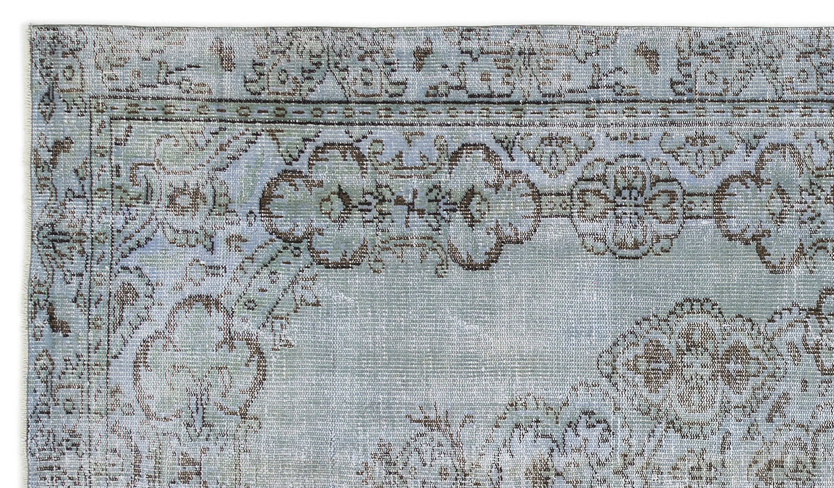 Light blue and grey distressed rug with a dark brown floral medallion border and traditional pattern.
