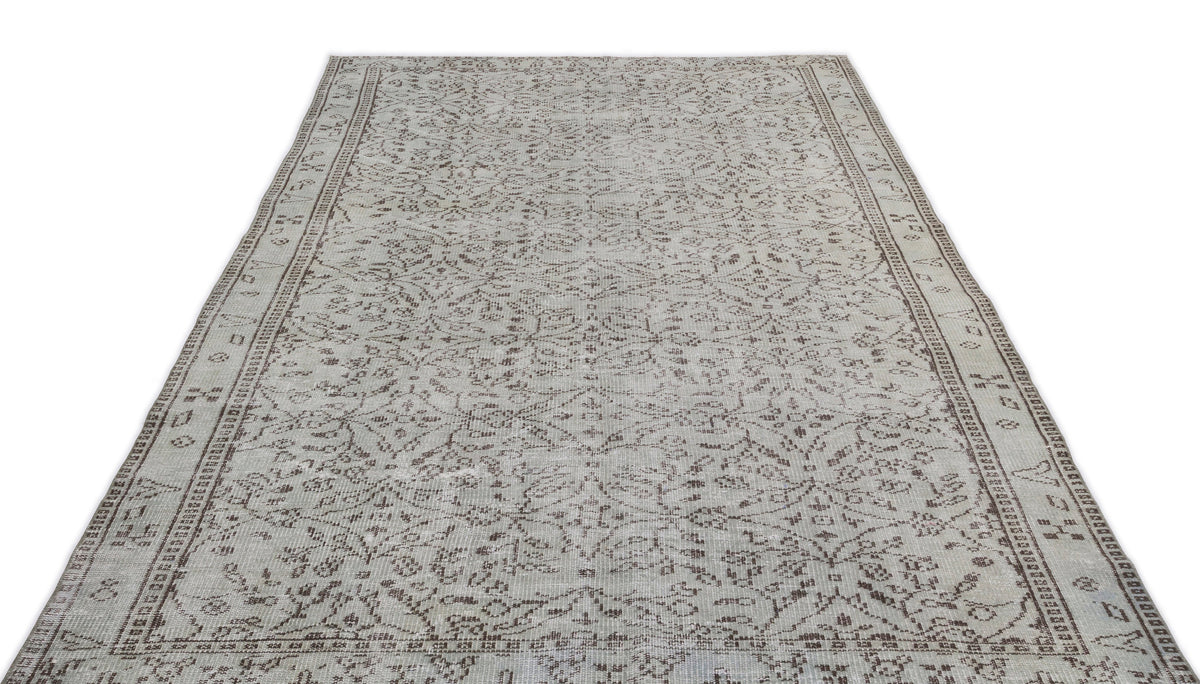 Light gray and brown vintage-style rug with a distressed floral medallion pattern and a decorative border.