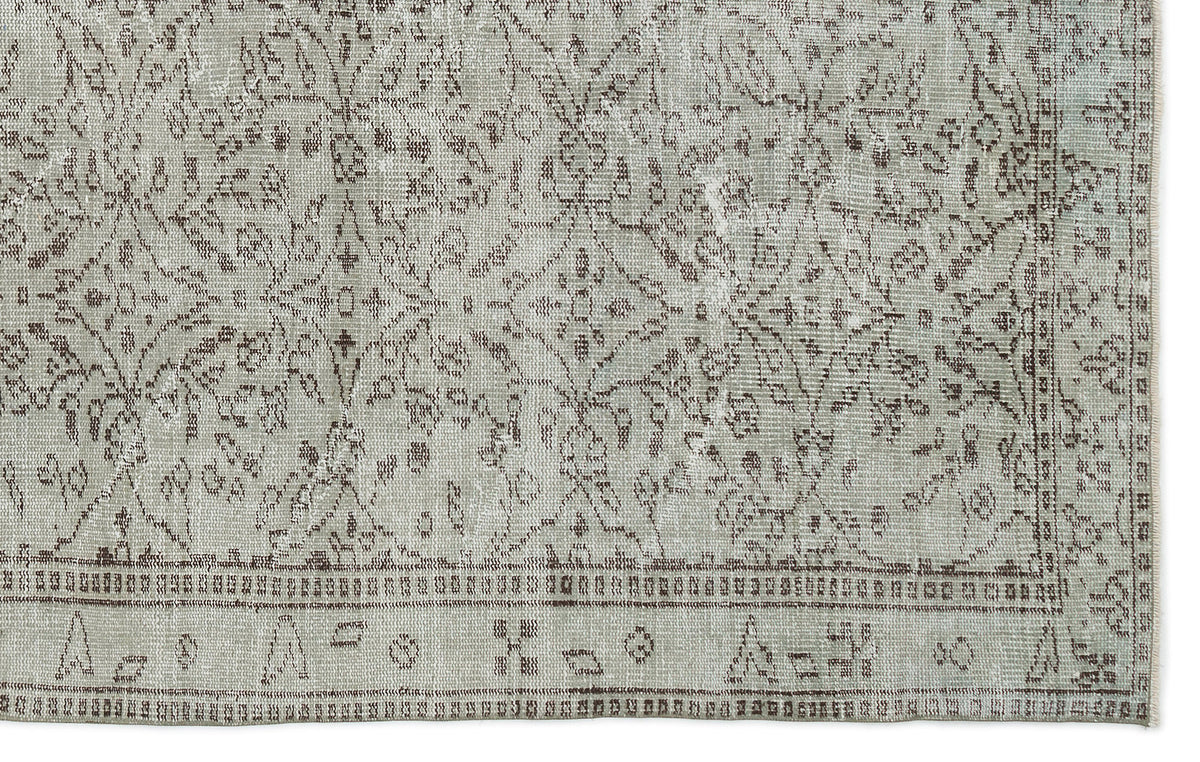 Light gray and brown distressed rug with a traditional floral medallion pattern and a geometric border.
