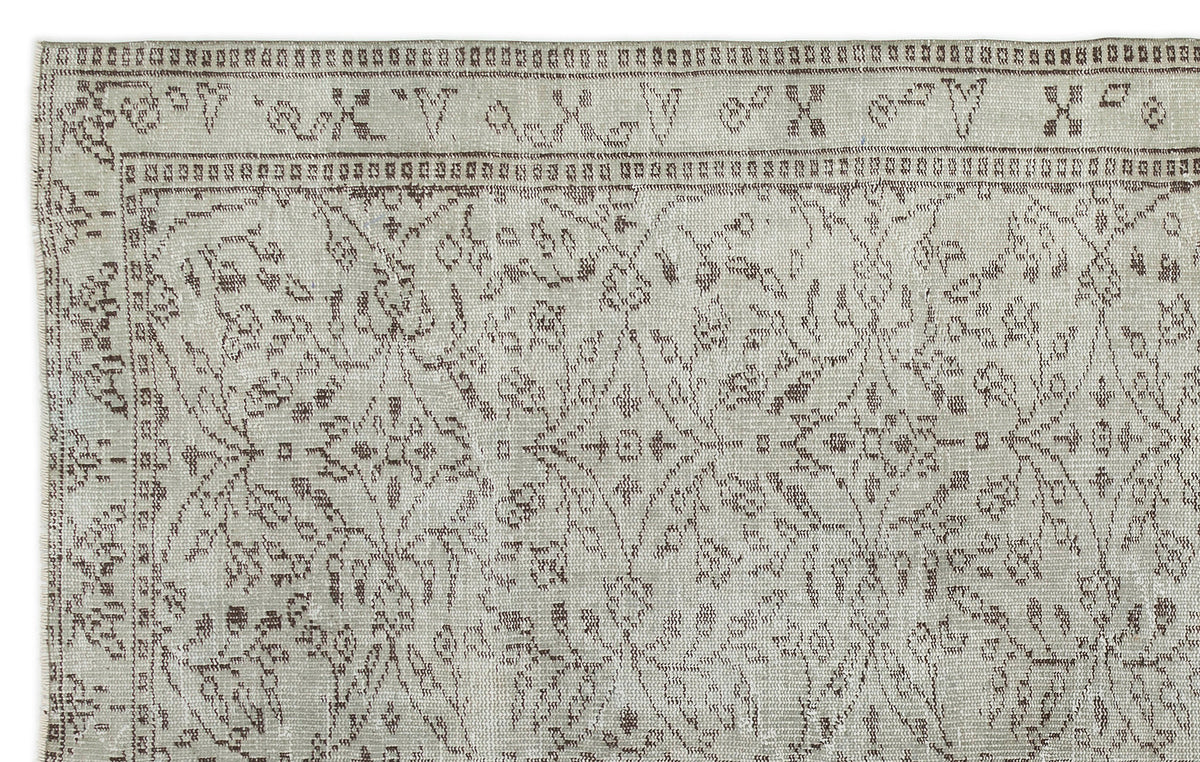 Light gray and brown vintage-style rug with a distressed floral medallion pattern and a geometric border.