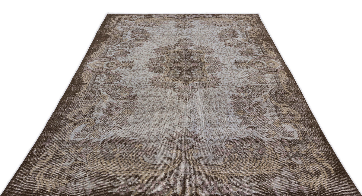 Brown and light grey vintage-style rug with a central floral medallion and ornate border on a white background.