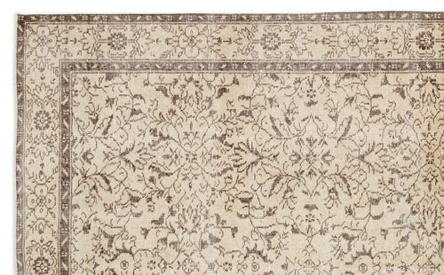 Load image 1 in gallery view. A close-up of the Trabiane - Vintage Floral Rug (6'1 x 9'11) shows its beige and brown tones with intricate floral and geometric patterns on the border and center, creating a classic, antique look.