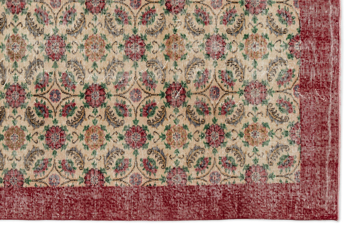 Beige rug with a repeating floral medallion pattern in red, green, and blue, featuring a wide distressed red border.