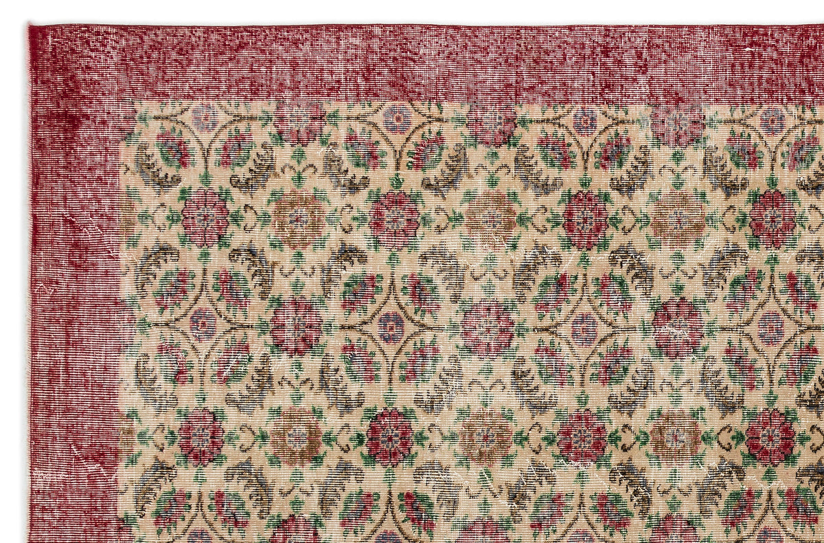Beige rug with a distressed red border and a repeating floral medallion pattern in red, green, and brown.