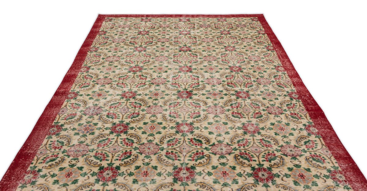 Beige rug with a red border and a repeating floral medallion pattern in red, green, and gold on a white background.