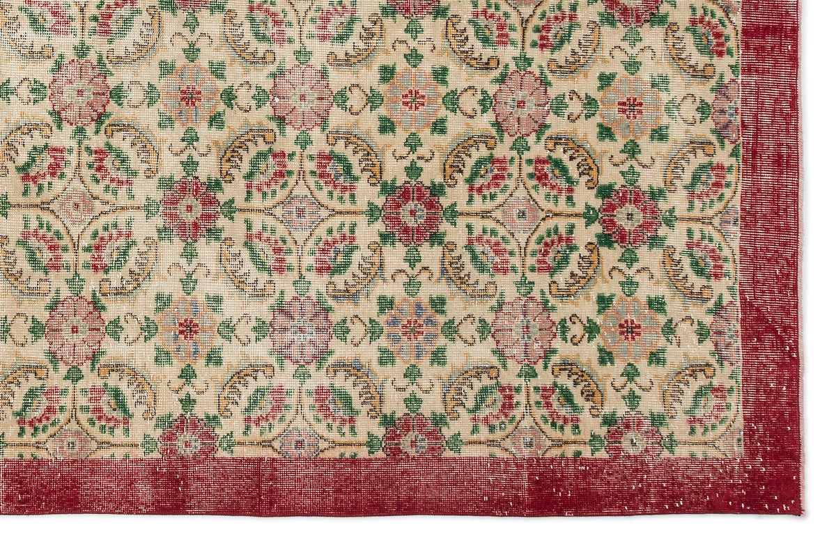Beige rug with a repeating floral medallion pattern in red, green, and gold, featuring a wide red border.
