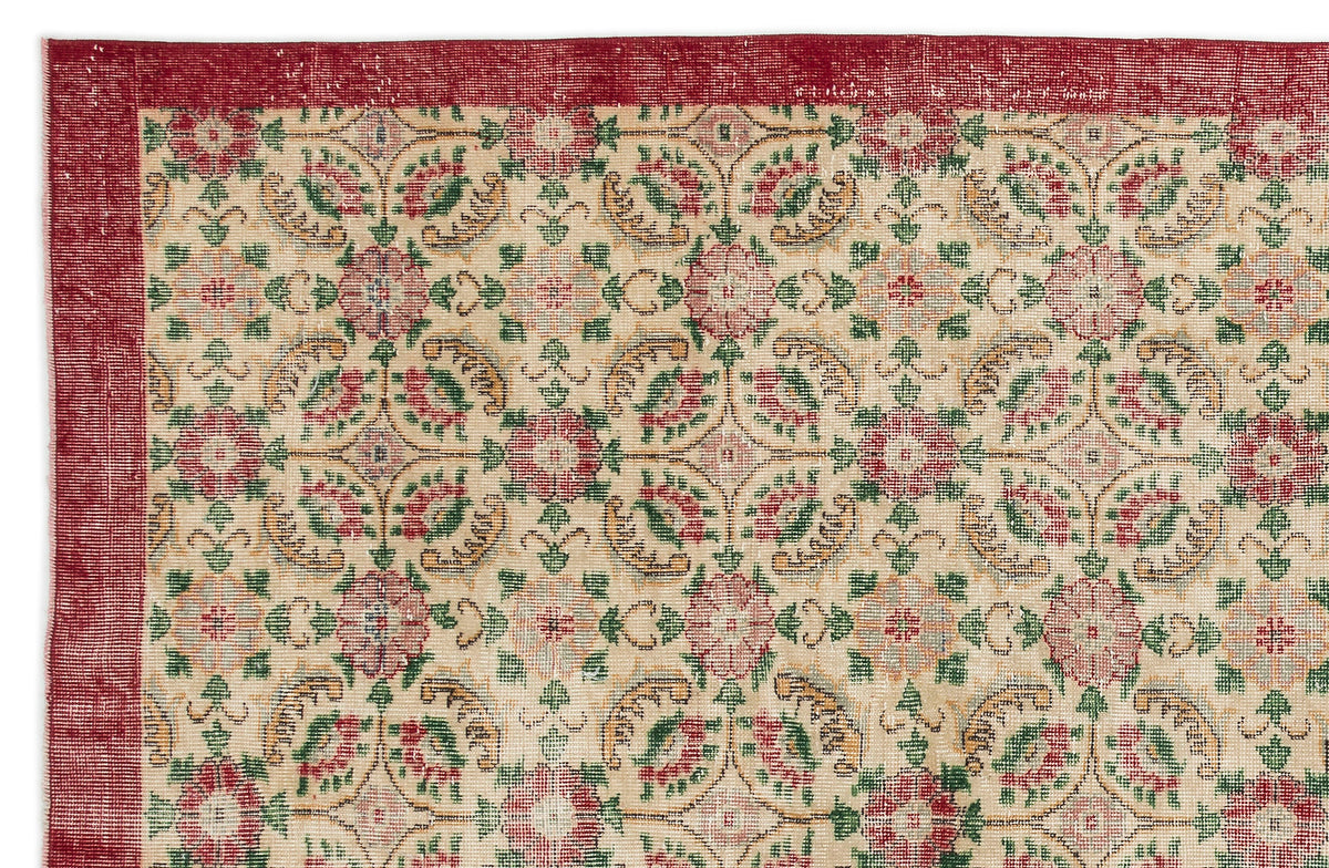 Beige rug with a red border and a repeating floral medallion pattern in red, green, and gold.