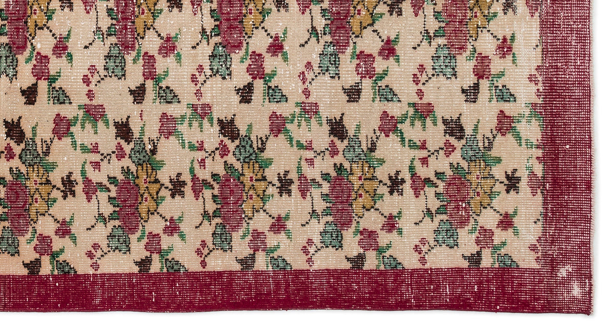 Beige rug with a distressed floral pattern in red, yellow, and green, featuring a solid red border.