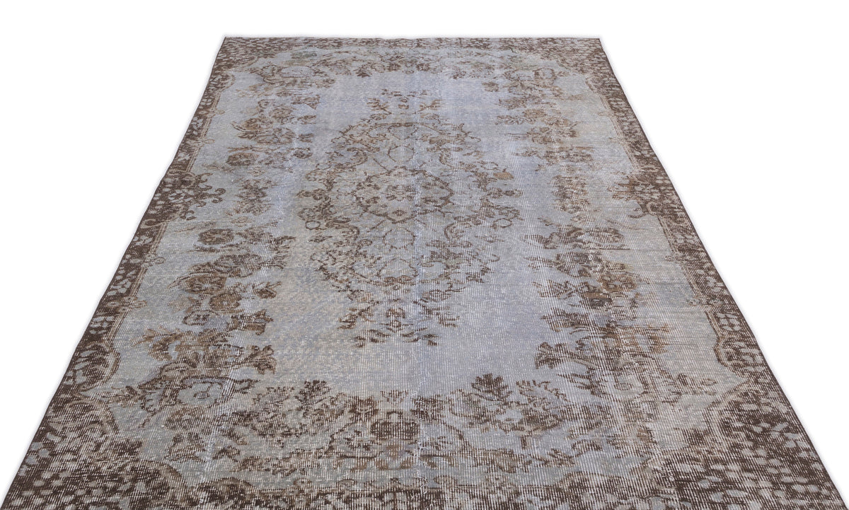 Light blue and brown distressed area rug with a traditional central medallion and ornate floral border.