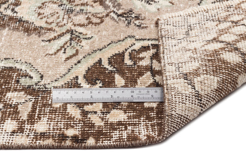 Load image 1 in gallery view. Beige and brown traditional floral medallion rug with a folded corner and a stainless steel ruler for scale.