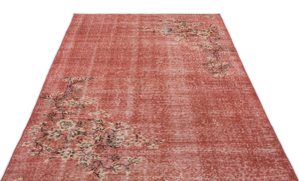 Distressed terracotta rug with an asymmetrical floral pattern in beige and dark brown on a white background.