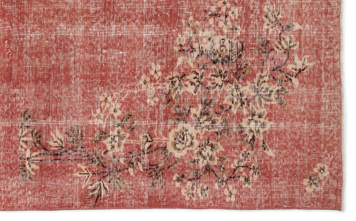 Distressed terracotta rug with a faded cream and brown floral branch pattern.