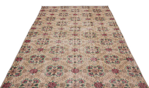 Load image 1 in gallery view. Beige vintage-style rug with a repeating floral medallion pattern in muted red and green on a white background.