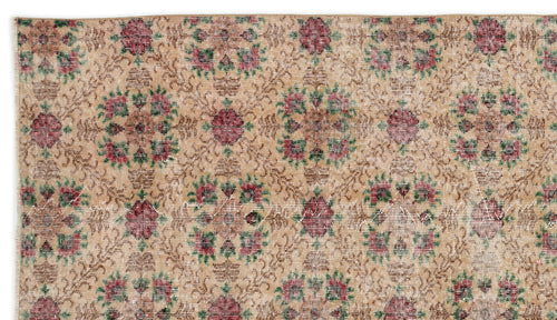 Load image 1 in gallery view. Tan vintage-style rug with a repeating floral medallion pattern in muted red and green on a distressed background.
