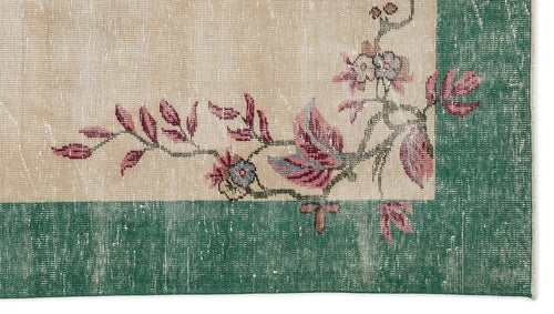 Load image 1 in gallery view. Beige rug with a distressed green border and floral vine pattern in shades of pink, blue, and green.
