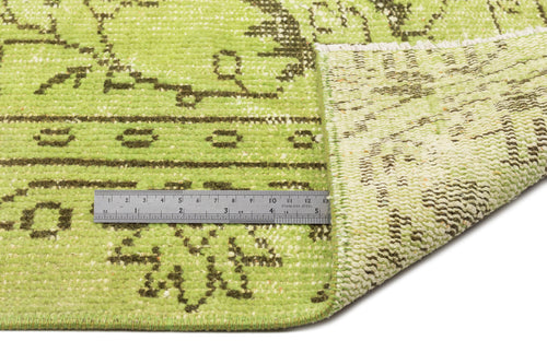 Load image 1 in gallery view. Lime green and dark brown distressed traditional rug with a folded corner and a metal ruler for scale.