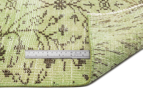 Load image 1 in gallery view. Light green rug with a distressed brown floral pattern and a metal ruler for scale on a white background.