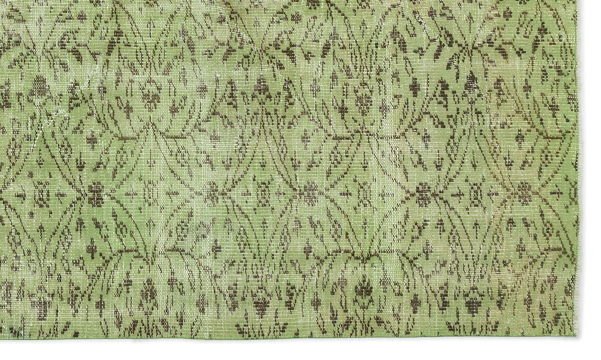 Sage green rug with a distressed brown diamond lattice pattern and intricate floral motifs.