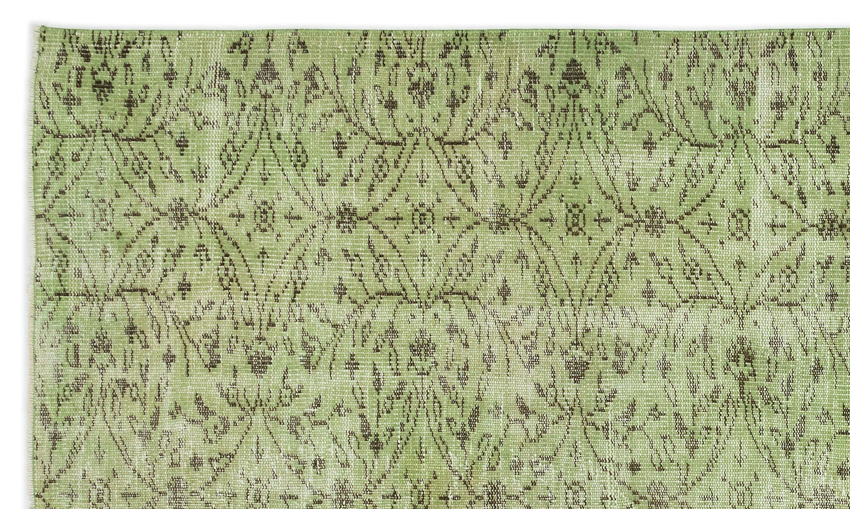 Sage green rug with a distressed, dark brown repeating diamond and floral medallion pattern.