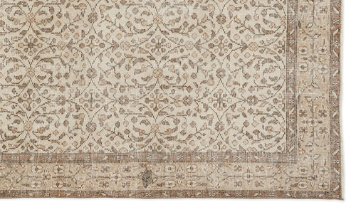 Load image 1 in gallery view. The Pavia - Vintage Floral Rug (5'7 x 9'5) is a beige and brown overdyed Anatolian hand-woven rug with geometric and floral designs, a wide patterned border, and a subtly distressed texture for vintage character.