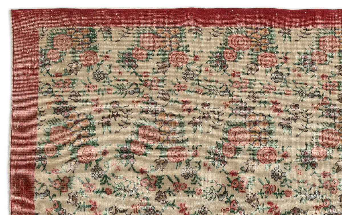 Beige rug with a red border and a repeating floral pattern in red, green, and dark grey.