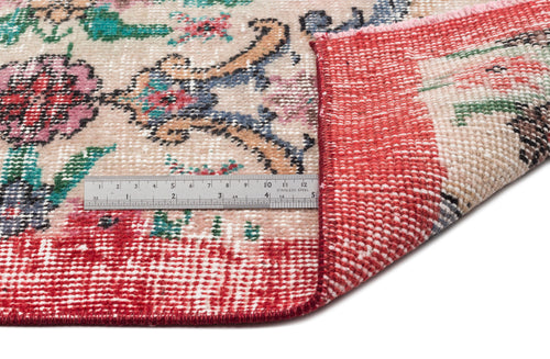 Load image 1 in gallery view. Beige rug with a floral medallion pattern in red, pink, and blue, shown folded to reveal the red woven backing and ruler.