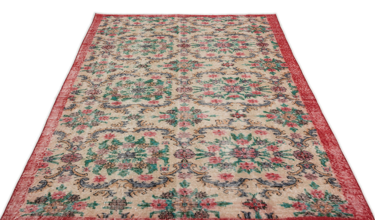 Beige vintage-style rug with a red border and repeating floral medallion pattern in red, green, and dark blue.