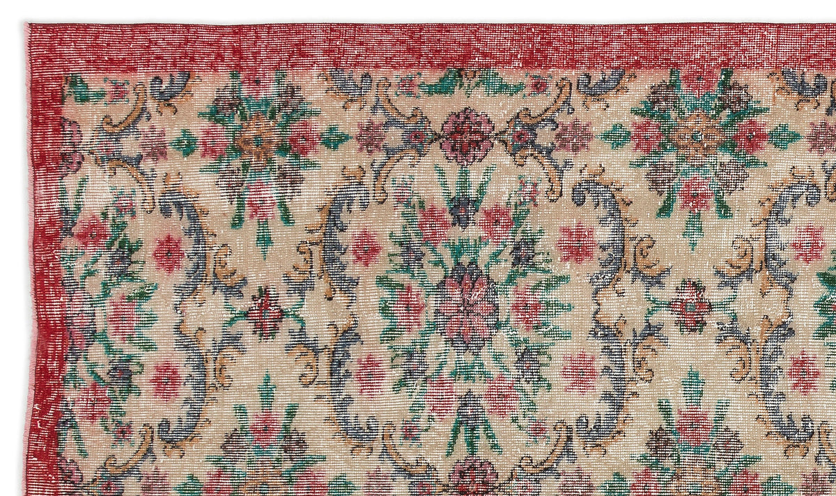 Beige rug with a red border and a distressed floral medallion pattern in red, green, and dark blue.