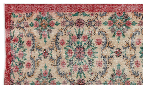 Load image 1 in gallery view. Beige rug with a red border and a distressed floral medallion pattern in red, green, and dark blue.