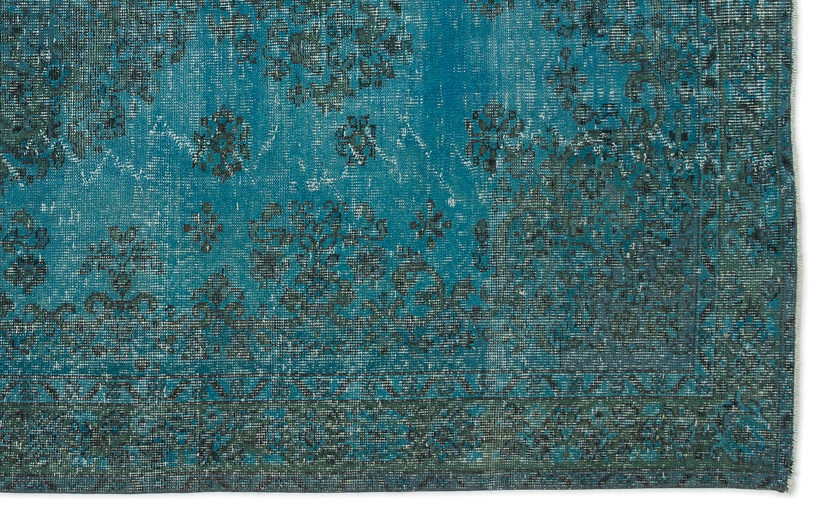 Teal and dark charcoal distressed rug with a faded traditional floral medallion pattern and a bordered edge.