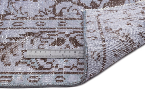 Load image 1 in gallery view. Light blue and brown distressed traditional rug with a metal ruler showing pile thickness on a white background.