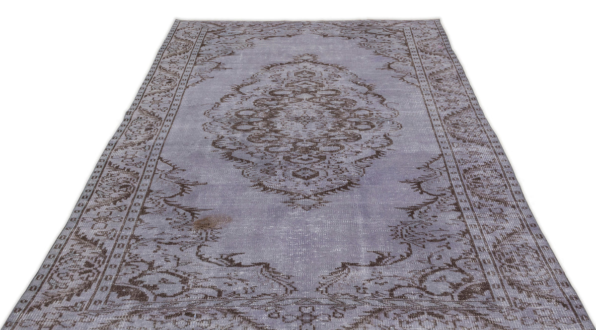 Lavender and brown distressed vintage-style rug with a central floral medallion and ornate border.